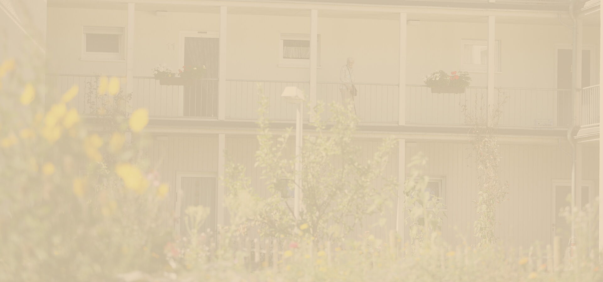 Abgetönte Hintergrundaufnahme eines gepflegten Gartens mit Holzzaun im Seniorendorf Reinery.