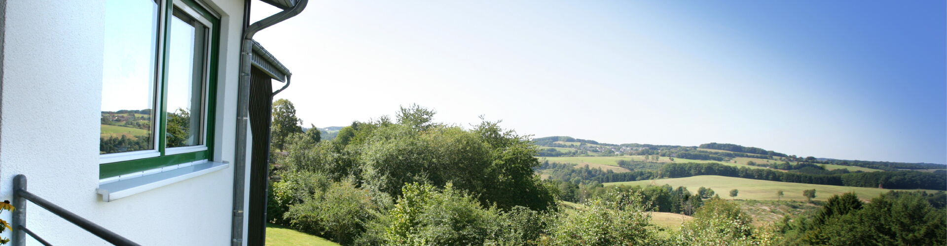 Weitläufiger Ausblick von einem Balkon der Wohnanlage über die hügelige, grüne Landschaft des Oberbergischen Kreises.