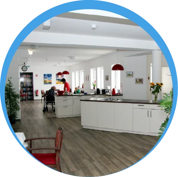 Innenansicht eines modern gestalteten, barrierefreien Wohnbereichs mit offener Küche und Blick in den Gemeinschaftsraum.