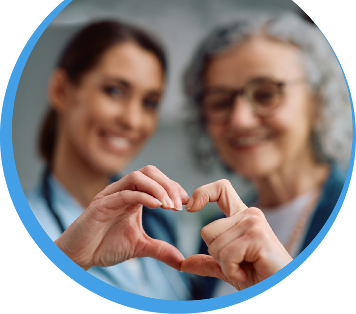Eine Pflegekraft und eine Seniorin formen mit ihren Händen gemeinsam ein Herz – Symbol für die herzliche Pflegequalität.