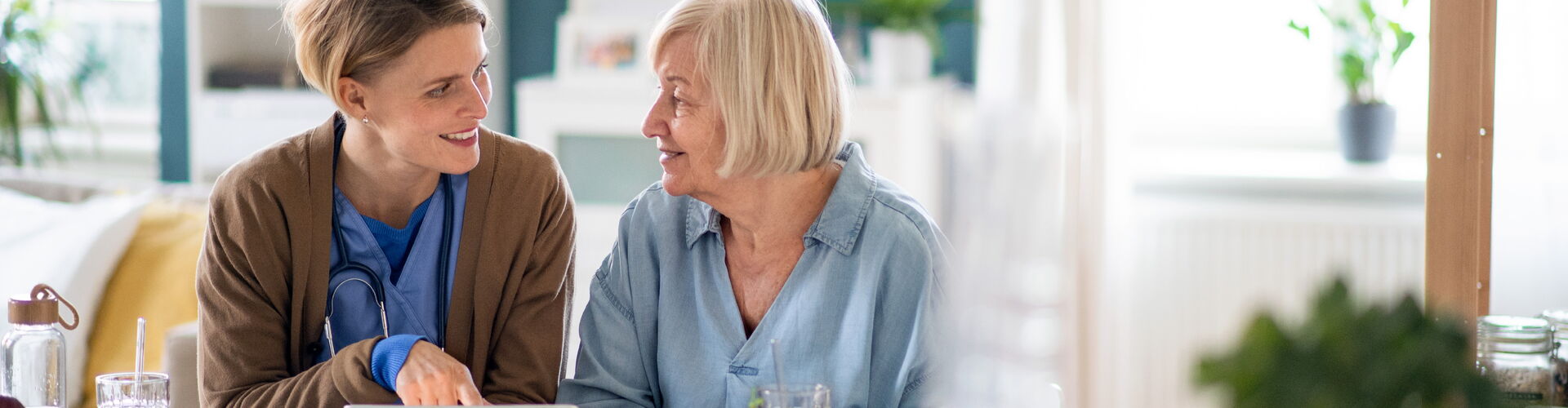 Eine Mitarbeiterin und eine Seniorin arbeiten konzentriert an einem Tablet – moderne Unterstützung und Teilhabe im Alltag.